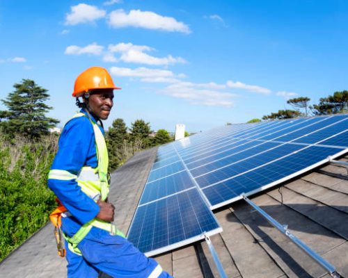 Team of blue collar workers installing solar panel on roof of building